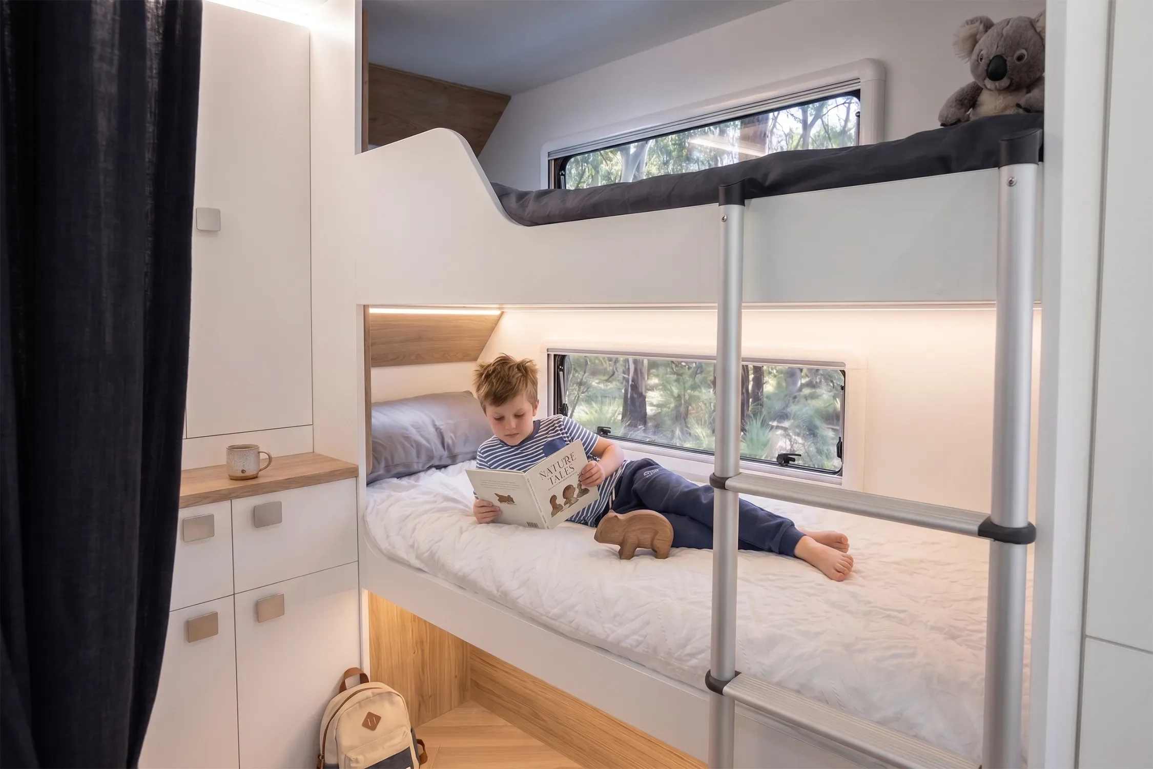 Road Owl bunk room with two bunks, ladder, windows for each bunk and a blockout curtain